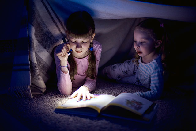 Kinder lesen und erzählen eine Geschichte auf einer Übernachtungsparty