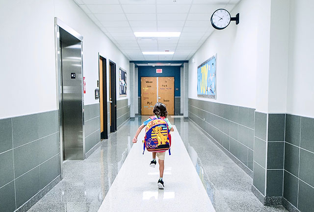 Kind läuft über den Gang einer Einzugsschule oder Wahlschule