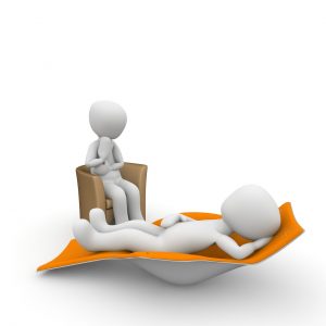 Zwei 3D-figuren in einer Therapiesitzung; eine Figur liegt entspannt auf einer Liege, während die andere auf einem Stuhl gegenüber sitzt. Ideal für Themen wie Psychologie, Therapie und Entspannung.