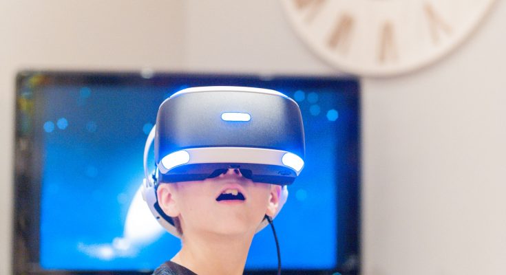 Junge mit Virtual-Reality-Headset steht vor einem Fernseher und erlebt eine digitale Welt. Die Atmosphäre ist modern und technologisch.