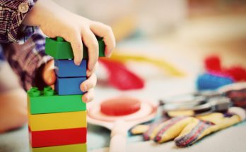 Eine Kleinkindhand baut mit Lego Duplo einen Turm.