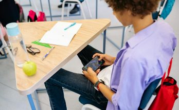 Schüler nutzt Handy in der Schulstunde.