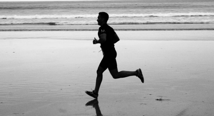 Ein Mann joggt am Strand entlang.
