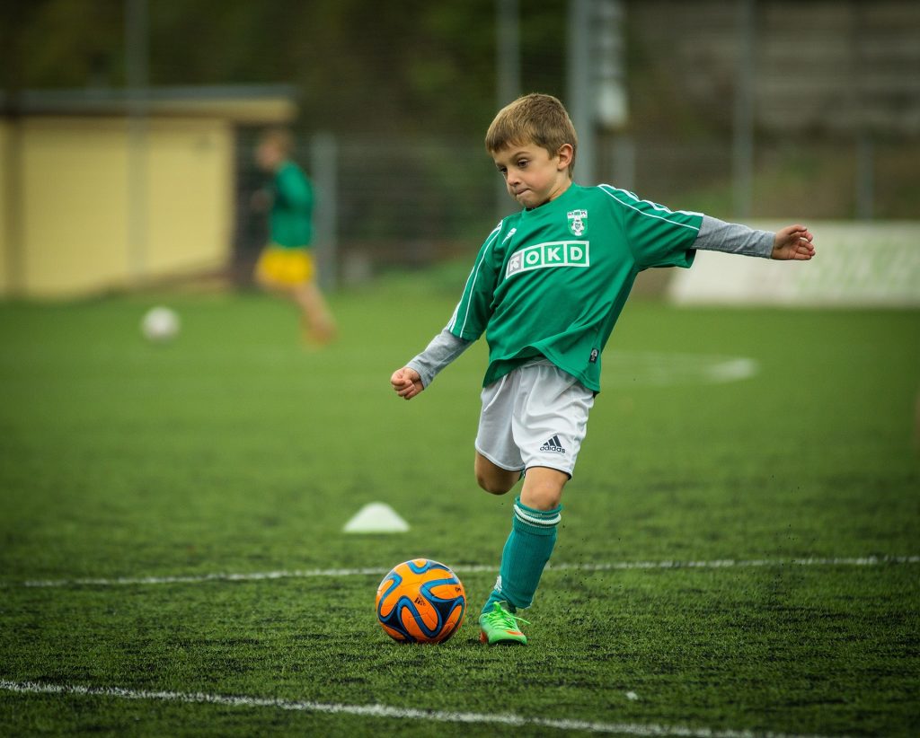 Kind spielt Fußball.