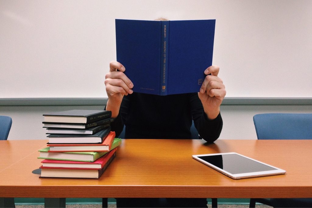 Mann mit Buch an einem Schreibtisch - Abbildung zum Artikel "Rückenschule".