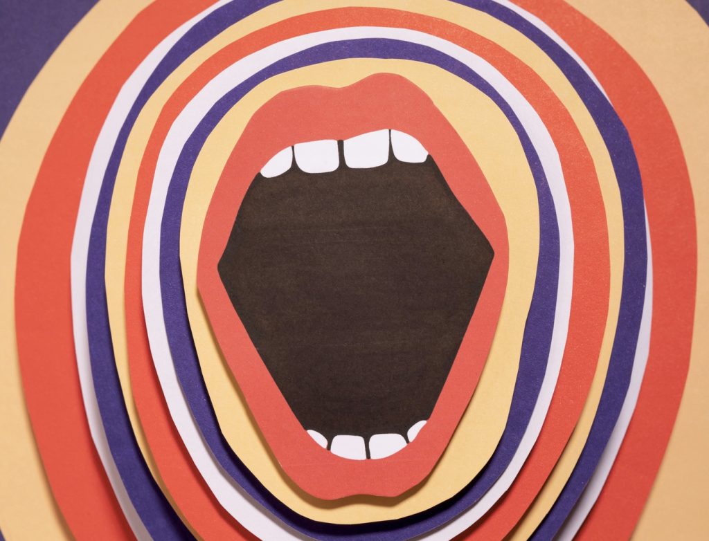 Buntes Papierkunstwerk mit einem stilisierten offenen Mund, umgeben von geschichteten, farbigen Ringen. Das Bild vermittelt Kreativität und Ausdruckskraft durch die Verwendung von verschiedenen Farben und Formen. Ideal für Themen wie Kunst, Design und Kommunikation.