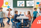 Eine Gruppe fröhlicher Kinder spielt im Klassenzimmer, während eine Lehrerin ein Buch vorliest. An der Wand hängen Bilder von Sonne, Wasser und Wind, die die Themen des Unterrichts illustrieren. Die Kinder interagieren spielerisch und zeigen Begeisterung für das Lernen.